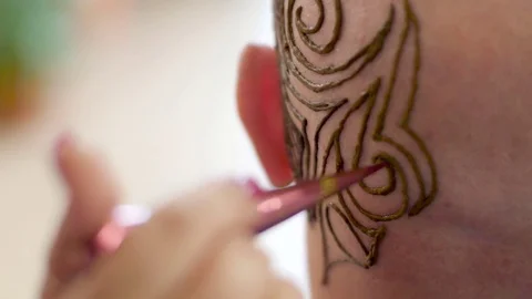 A close-up, a master, an artist mehendi drawing a tattoo, a picture of henna on Stock Footage
