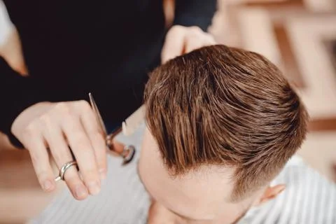 Close-up master Barber does hairstyle and styling with dryer hair to guy 스톡 사진