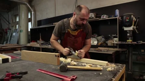 Close up master carpenter in an apron planes tree with a plane in workshop Stock Footage 157105713