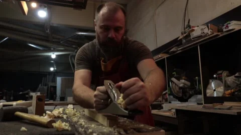 Close up master carpenter in an apron planes tree with a plane in workshop Stock Footage 157105924