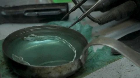 Close-up master jeweler boils a silver bracelet in a chemical solution Stock Footage 126726650