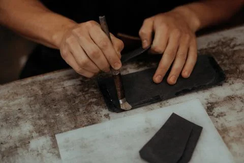 Close up of master making leather wallet with brush and glue. Handmade master at Stock Photos