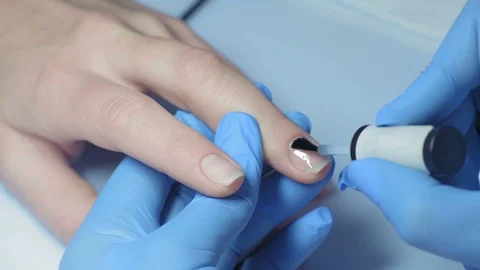 Close-up, Master Manicure Applies a Layer of Protective Varnish on the Girl's Stock Footage 97959485