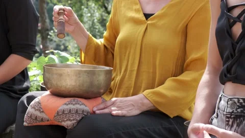 Close-up of a master playing a Tibetan singing bowl to help the class meditate Stock Footage 161397064