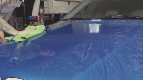 Close up of master polishing deep blue car in workshop, slow motion Stock Footage 82322702