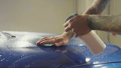 Close up of master polishing deep blue car in workshop, slow motion Stock Footage 82331166