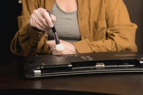 A close-up of the master technician clears the dust from an old laptop. compu Stock Photos