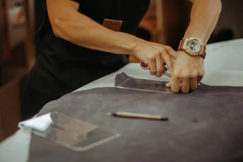Close up of a master working with leather textile at his workshop using tools Stock Photos