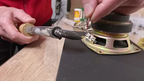 Close-up of a master's hand soldering two wires to a sound column. The solder Stock Footage 130779752