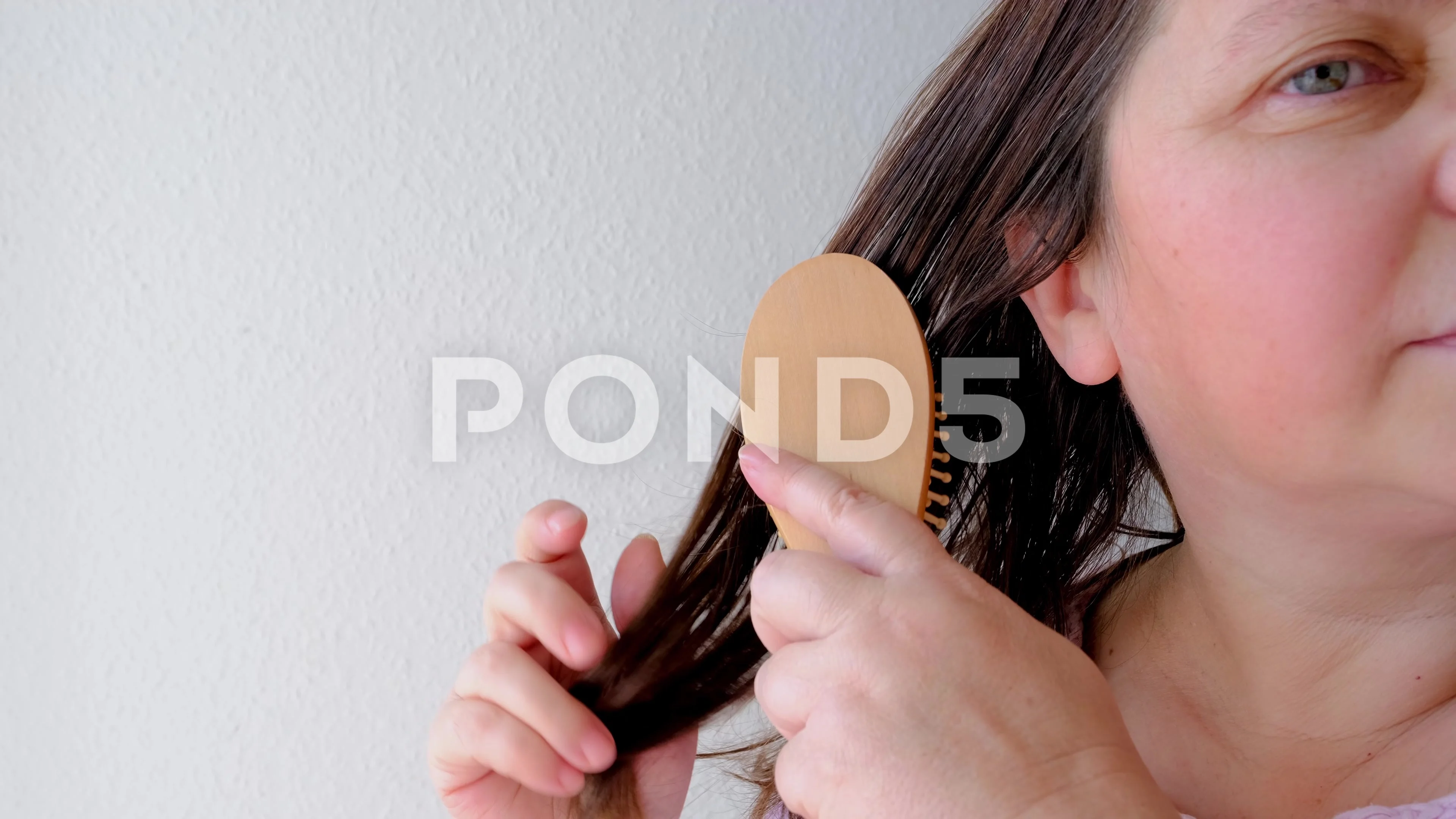 close-up of mature adult woman combing dirty greasy hair with a wooden  mass..