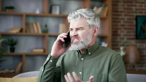 Close up of mature bearded man with gray hair arguing on smartphone at home.  Stock Footage 328706751