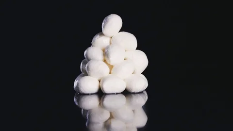Close up of mazarela cheese that rolls over black background in slow motion. Stock Footage 112647931
