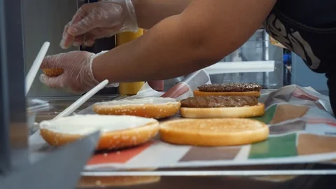 Close-up of McDonald workers cooking classic hamburgers with fried cutlet Stock Footage 105535440
