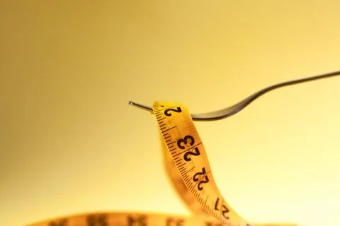 Close up of a measuring tape on a fork over a yellow background Stock Photos