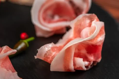 Close up of meat appetizer with prosciutto, ham on black slate background Foto stock