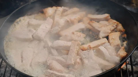 Close-up of meat being fried in frying pan over bonfire in forest Stock Footage 308719889