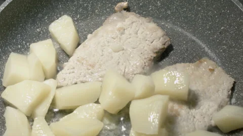 Close-up of meat chops in a frying pan warmed up with potatoes. Vídeo Stock 135201410