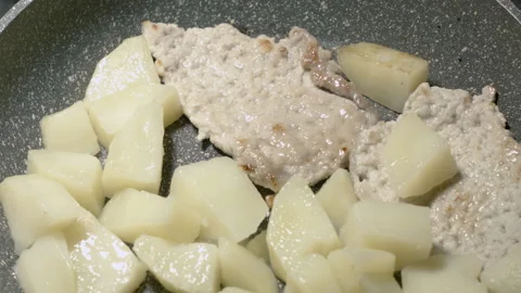 Close-up of meat chops in a frying pan warmed up with potatoes. 스톡 동영상 135214219