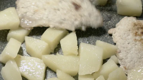 Close-up of meat chops in a frying pan warmed up with potatoes. 스톡 동영상 135214321