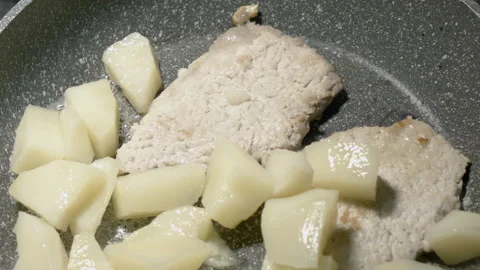 Close-up of meat chops in a frying pan warmed up with potatoes. 스톡 동영상 135214326