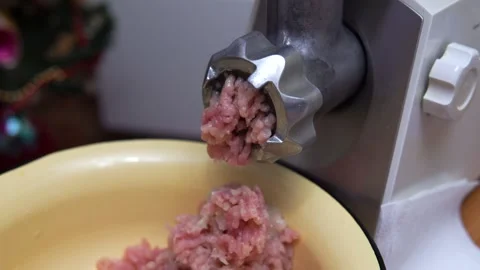 A close-up of a meat grinder dispensing pink ground meat into a yellow bowl Stock Footage 325102909
