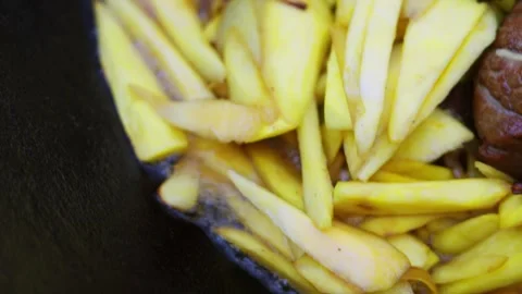 Close-up of meat, onion and sliced carrots frying in hot oil in a large cauldron Stock Footage 346539555