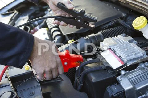 Close-Up Of Mechanic Attaching Jumper Cables To Car Battery Stock Photos