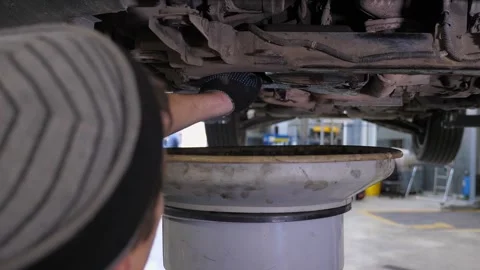 Close-up mechanic drains excess engine oil for the required pressure in the car. Stock Footage 337734537
