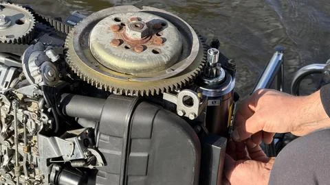Close up of mechanic hands adjusting components on an open outboard marine 库存照片