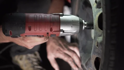 Close up of mechanic hands changing tire with drill Video stock 114577452