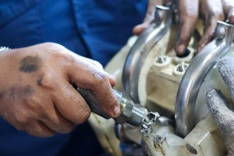 Close up of a mechanic hands working on an engine assembly component in a w.. Stock Photos