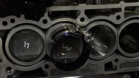 Close-up of mechanic installing a piston into a car engine block. Video stock 332064824
