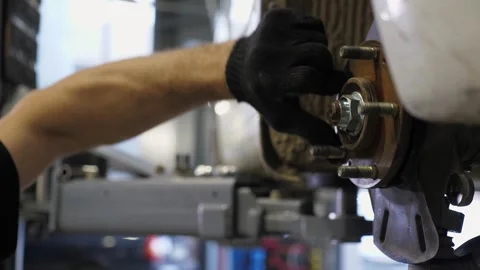 Close-up of a mechanic replacing brake pads on a car wheel at a service station. Stock Footage 336666717