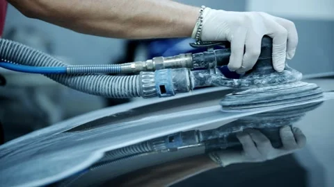 Close-Up of a Mechanic Sanding a Car Panel with a Power Sander Stock Footage 318309703