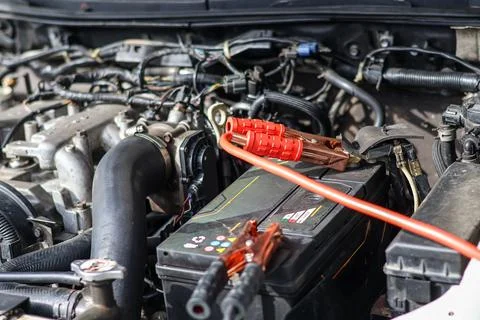 Close up of a mechanic technician using red jumper cables. Stock Photos
