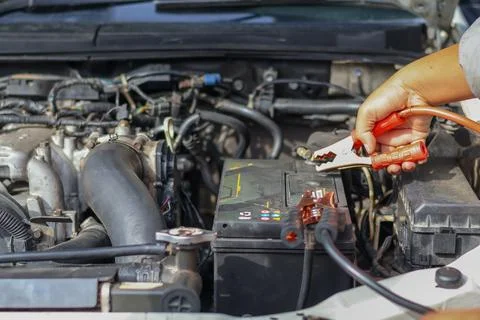 Close up of a mechanic technician using red jumper cables. Stock Photos