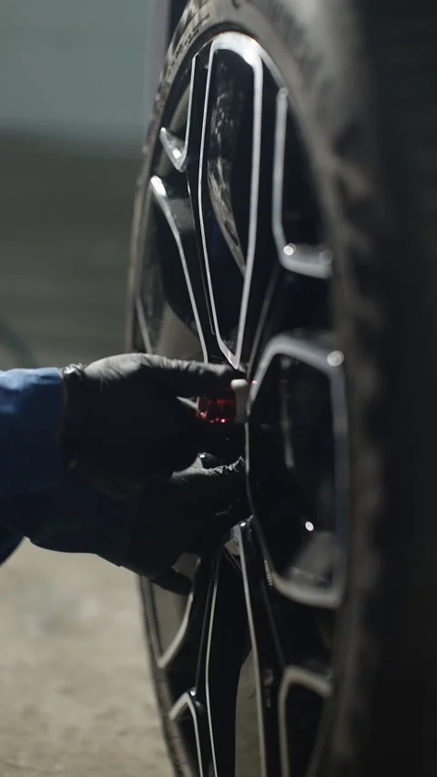 Close-up of a mechanics gloved hand adjusting the center hub of a glossy black Stock-Footage 334181653