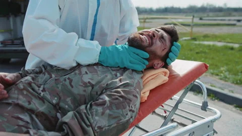 Close up medic provides first aid to wounded soldiers scream in pain in Stock Footage 187687487