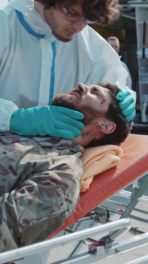 Close up medic provides first aid to wounded soldiers scream in pain in Stock Footage 281345336