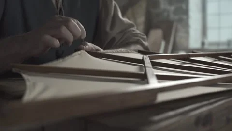 Close up of medieval inventor hands hemming the edge of canvas on a wing Stock Footage 338992167