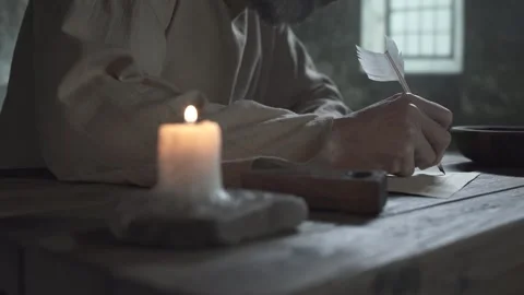 Close up of medieval prisoner hands writing with a quill pen on a wooden table Stock Footage 340823985