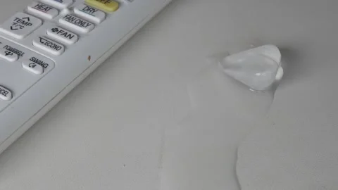 Close-up of a melting ice cube next to a air conditioning remote. Summer home Stock Footage 342809292