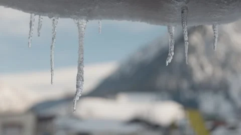 Close Up of Melting Icicles Dripping Water Drops with Blurred Snowy Mountains Stock Footage 327650045