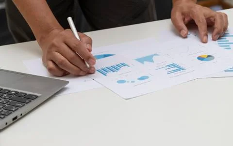 Close up men hand working on desk with a laptop computer, and business chart Stock Photos