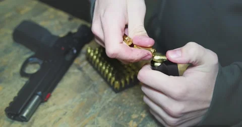 Close up of men hands loading ammo in pistol magazine Stock Footage 232500867