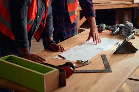 Close-up of men in reflective clothing gesturing at paper near digital tablet in Stock Photos