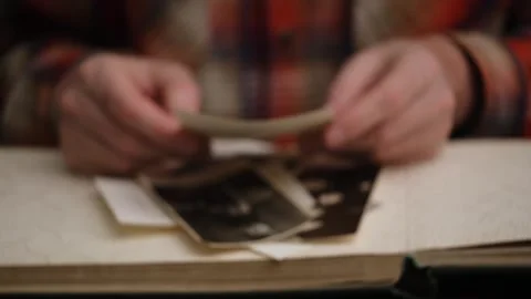 Close-up men's hands carefully sorting through old photos in blurry. front view. Stock Footage 305621385