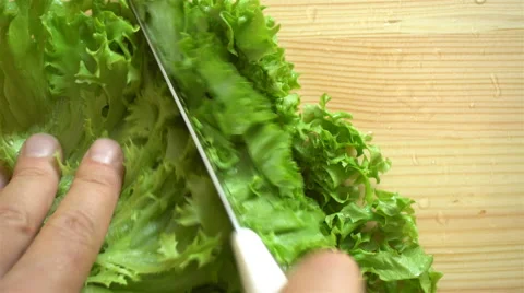 Close-up. Men's hands cut green lettuce on wooden surface. Top view. Stock Footage