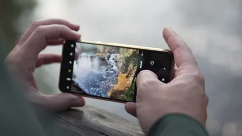 A close-up of men's hands with a phone makes a photo of beautiful autumn nature Stock Footage 140663510