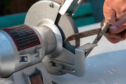 Close-up of men's hands sharpening scissors on an electric sharpener. Repair Stock Photos